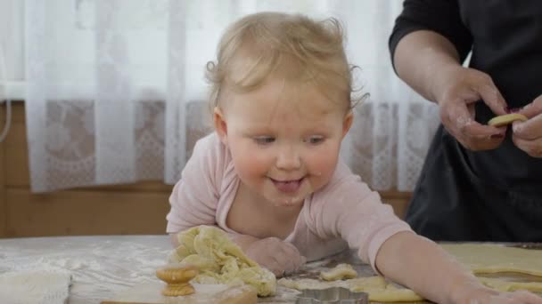 Petite fille goûte de la pâte pour les biscuits de vacances et sourires drôles. Gros plan. — Video