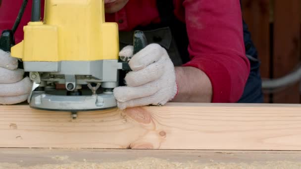 Csucasian stolarz przetwarza belkę drewnianą z frezarką. — Wideo stockowe