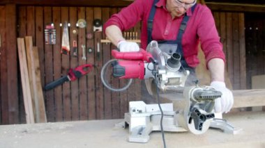 Erkek marangozun yakın çekimi kiriş parçasını testereyle testereyle keser ve talaş uçurur.