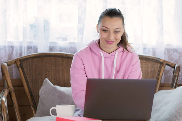 Joven hermosa mujer en ropa casual trabaja en el ordenador portátil desde casa, estudiando en línea — Foto de Stock