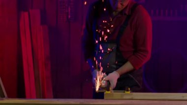 İşçi, metali çim biçme makinesiyle keser. Kıvılcımlar ve duman yavaş çekimde uçar