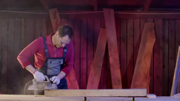 Menuisier masculin nettoie la surface de la poutre en bois à l'aide d'une raboteuse électrique en atelier — Video