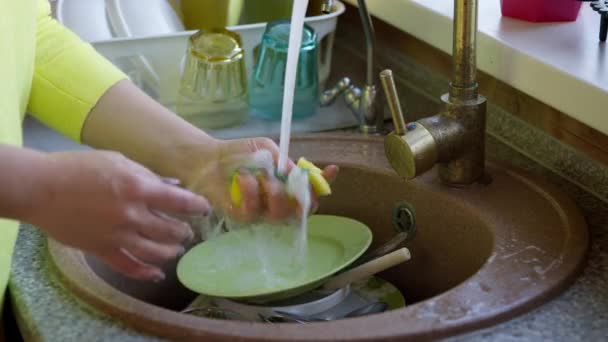 Hausfrau wäscht schmutzige Glasschale mit Schwamm und Waschmittel in der Spüle. — Stockvideo