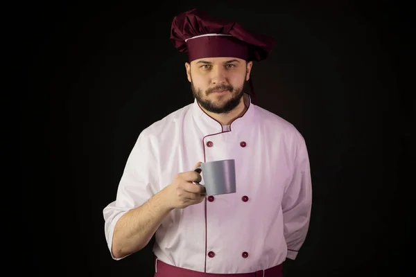 Glimlachende jonge bebaarde chef-kok met pet. beginner chef op zoek naar camera — Stockfoto