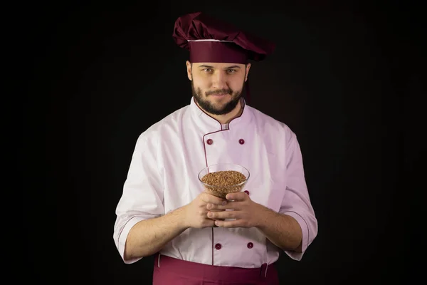 Молодий усміхнений майстер шеф-кухар у формі тримає миску з зернових. концепція природної їжі — стокове фото
