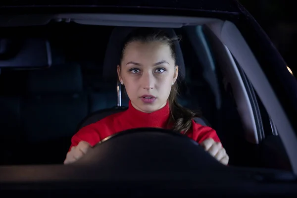 Mujer conduciendo coche por la noche. Conductora seria sentada dentro del viaje nocturno en coche — Foto de Stock