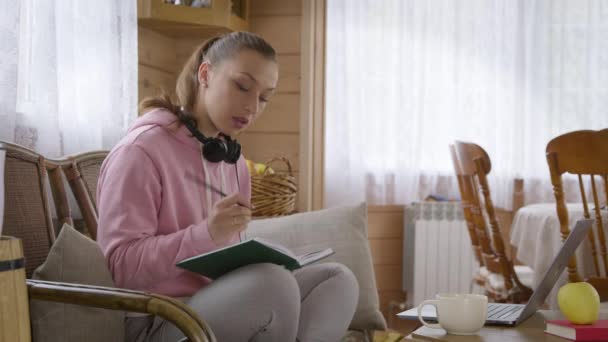 Pembe kapüşonlu genç beyaz kız karantina sırasında evde ders çalışıyor.. — Stok video