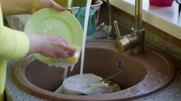 गृहिणी स्पंज और डिटर्जेंट के साथ सिंक में भोजन के बाद गंदी प्लेट धोती है — स्टॉक वीडियो