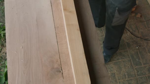 Male carpenter polishes surface of wooden bar with electric planer in workshop. — Stock Video