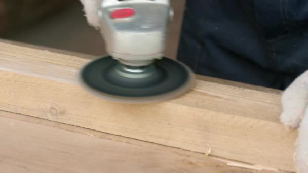 Чоловічий тесляр полірує поверхню дерев'яного бруска з кутовою шліфувальною машиною — стокове відео