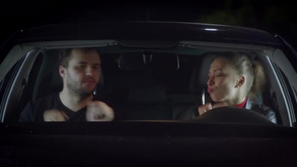夜に車の中に座って踊る幸せな美しいカップルは、楽しみを持って — ストック動画