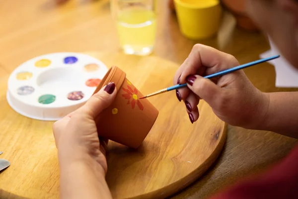 Cerca de las manos de las pinturas de artistas femeninos en la olla de cerámica de arcilla, taller de cerámica de arte — Foto de Stock