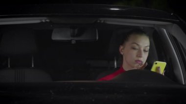 Bir kadın araba kullanıyor ve akıllı telefon kullanıyor..