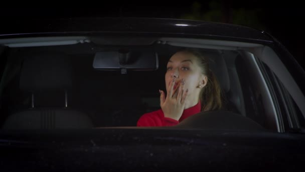 女の子は車を運転し、鏡を見て自分自身を賞賛し、化粧をしません. — ストック動画