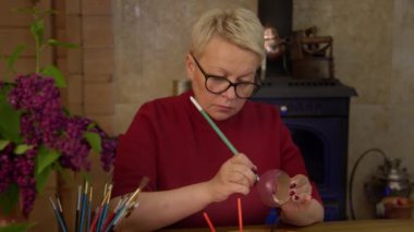 Sanat atölyesindeki ahşap mücevher bileziğine resim çizen güzel bir kadın.