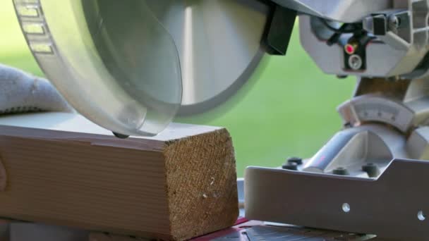 Cutting off 4x4 wooden post on mitre saw close-up. Circular saw blade in motion — Stock Video