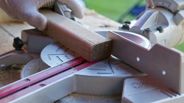 El carpintero fija el ángulo de la sierra de mitra 30 grados y corta la pieza de madera diagonalmente — Vídeo de stock