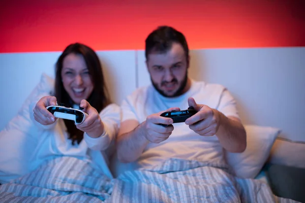 Couple d'amoureux jouant à des jeux vidéo au lit. Loisirs communs, valeurs partagées — Photo