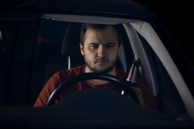 Sarhoş sürücü elinde bir şişe birayla araba kullanıyor..