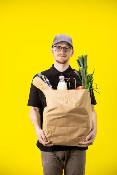 delivery man carrying paper bag of grocery food and drink from store