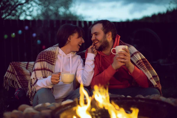 Happy Lovers communicate and laugh by the fire. Rest in the country.