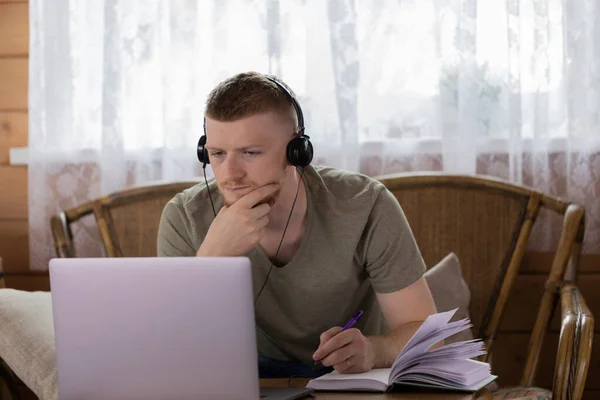 Homem caucasiano faz curso on-line na Internet usando um laptop na sala de estar . — Fotografia de Stock