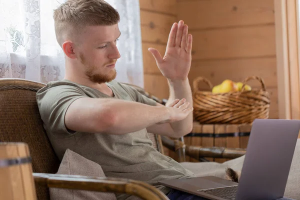 Hombre guapo muestra gestos al comunicarse en las redes sociales utilizando el ordenador portátil — Foto de Stock