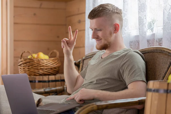 Guapo sonriente hombre se comunica con los padres en Internet mediante un ordenador portátil . — Foto de Stock