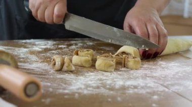 Yakın plan kadınların elleri tarçınlı şekeri bıçaklı hamur işiyle dilimler.