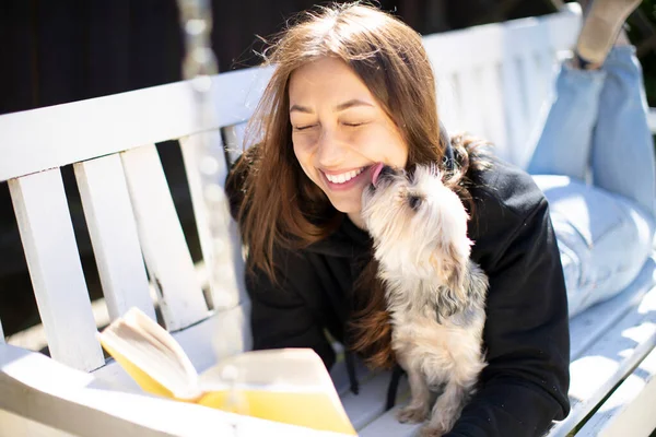 Köpek, gülümseyen güzel bir kızın yüzünü yalıyor..