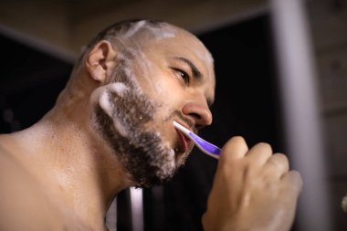 Duş alırken diş fırçasıyla dişlerini fırçalayan genç yakışıklı, kapat.