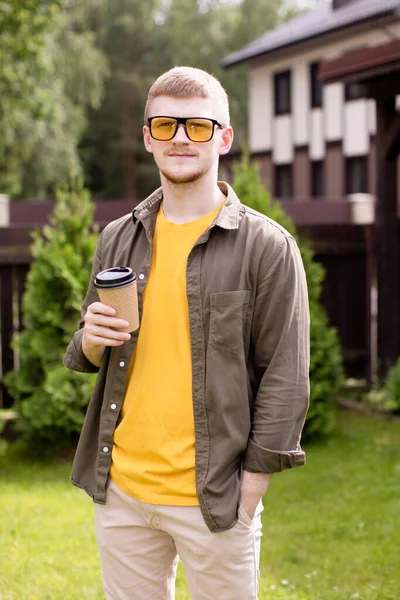 Genç hippi adamın portresi dışarıda duruyor, parkta bir fincan çayla dinleniyor.