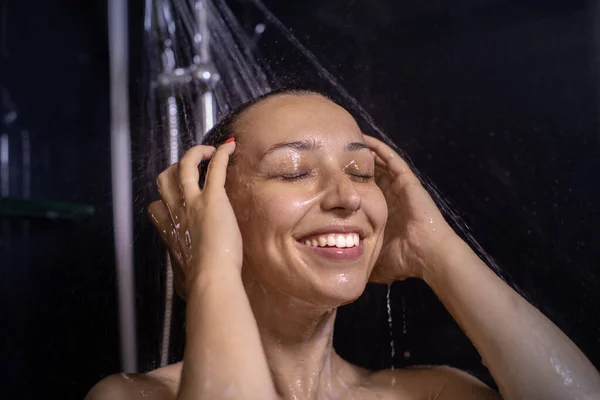 Happy beautiful woman standing in shower cabin, smiling lady enjoying showering — Stock Photo, Image