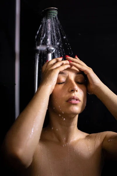 Όμορφη νεαρή γυναίκα απολαμβάνει τη ροή του νερού, κάνοντας ντους, κλείνοντας τα μάτια — Φωτογραφία Αρχείου
