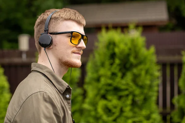 Pensive young handsome man in headphones listening educational podcast radio — Stock Photo, Image