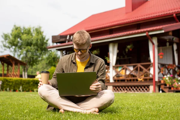 Young handsome man in casual wear resting sitting on lawn near home