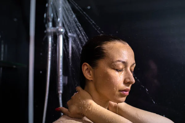 Attraente donna nuda con gli occhi chiusi rilassarsi sotto gocce d'acqua in cabina doccia — Foto Stock