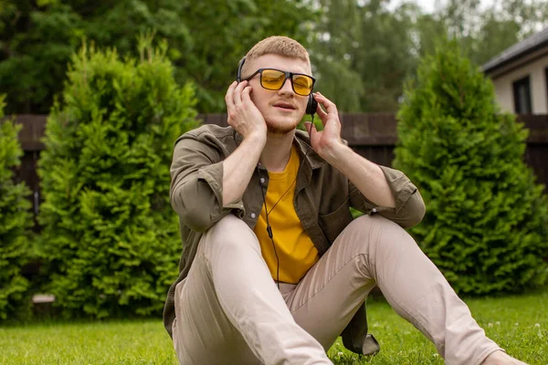 Hombre feliz se pone los auriculares escuchar música escalofriante con los ojos cerrados — Foto de Stock