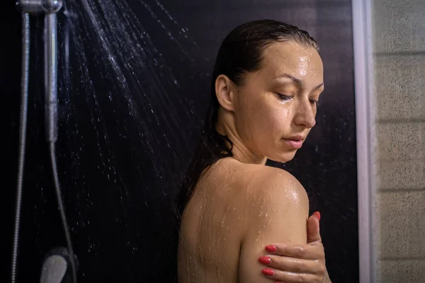 Naken ung kvinna njuter av rinnande vatten, duschar i badrummet blundar — Stockfoto