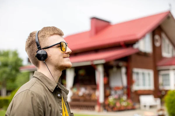 Positive young handsome man in headphones standing outdoors, podcast radio — Stock Photo, Image