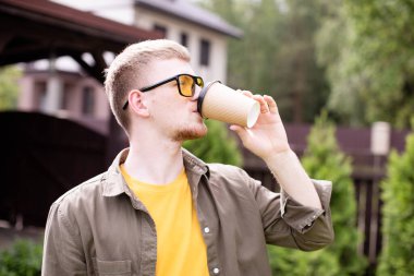 Genç milenyum adamı dışarıda kahve içiyor, parkta dinleniyor, dinleniyor.