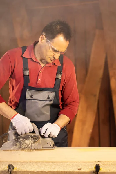 Google 'da çalışan orta yaşlı erkek marangoz elektrik planörüyle çalışma tezgahında çalışıyor. — Stok fotoğraf
