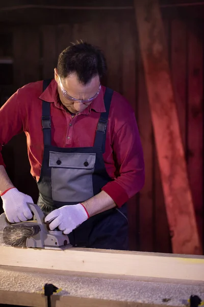 Middle-aged male craftsman working on workbench with electric planer — Stock Photo, Image