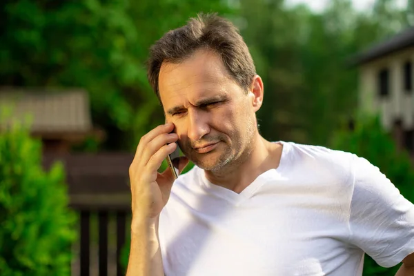 Vista de cerca del hombre guapo confiado que habla en el teléfono móvil al aire libre — Foto de Stock