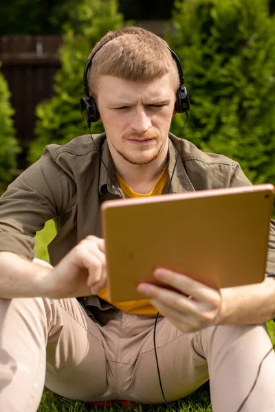 Cierre hombre seguro en los auriculares viendo webinar, trabajando en la tableta digital — Foto de Stock