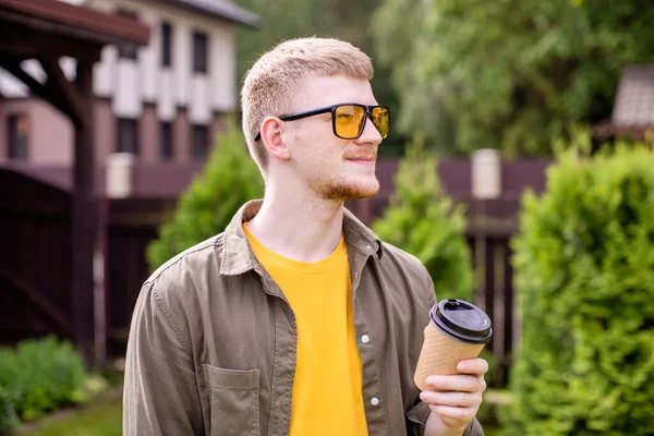 Joven empresario inteligente de pie al aire libre con una taza de café, joven progresista — Foto de Stock