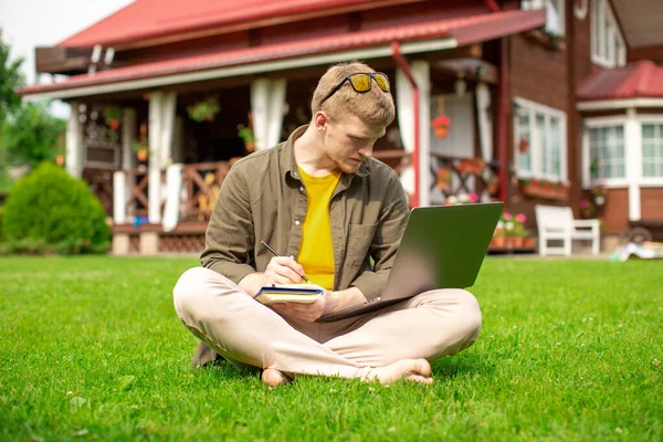 Hombre joven estudiando al aire libre viendo webinar educativo, toma notas en el diario — Foto de Stock