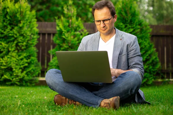 Adulto hombre de negocios inteligente trabaja en el ordenador portátil al aire libre, en línea traiding, e-commerce — Foto de Stock