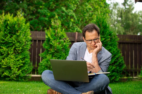 Multitarea. Empresario al aire libre sostiene portátil, portátil, conversaciones en el teléfono móvil — Foto de Stock