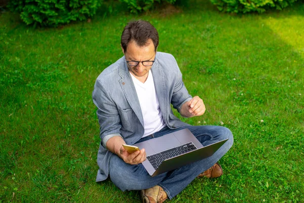 Hombre de negocios de mediana edad trabaja con el teléfono móvil portátil al aire libre, vacaciones ocupadas — Foto de Stock